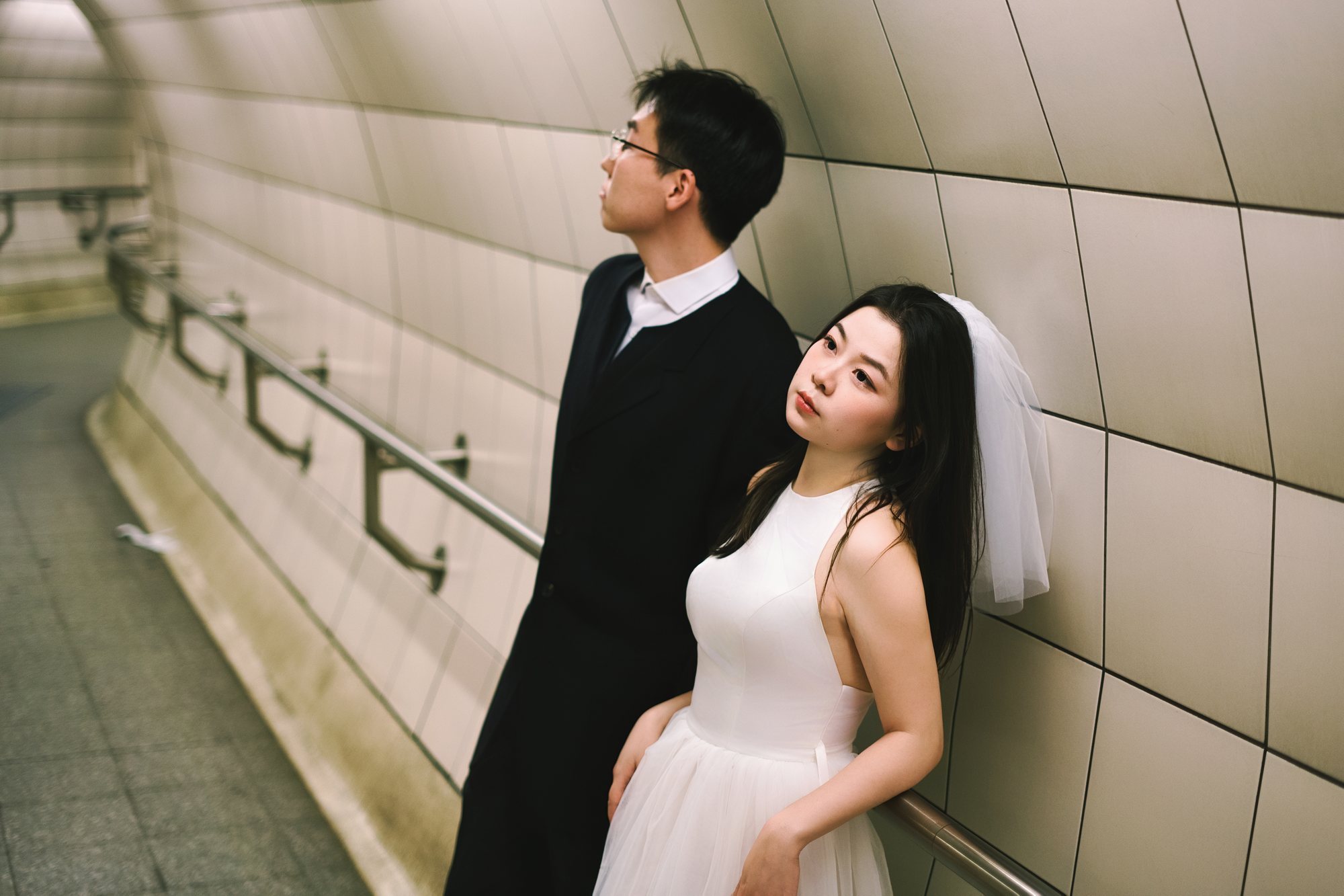 A couple photographed beside a tiled station wall